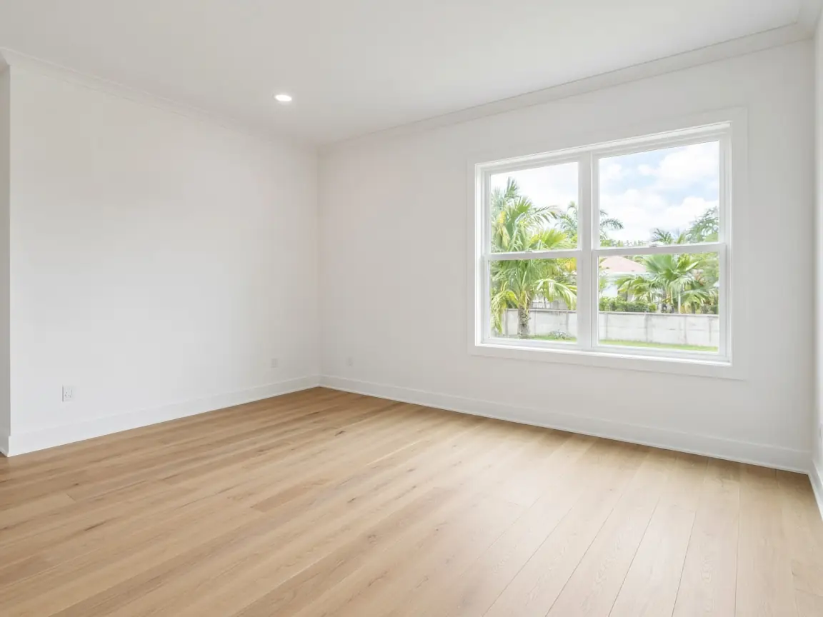 Empty unfurnished living room with light wood floor and a large window in a Florida rental